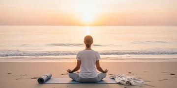 Woman meditating by the ocean during a sunrise wellness micro-vacation.